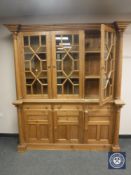 A heavily carved pine glazed inverted break fronted bookcase fitted with cupboards and drawers