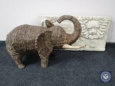 A large wicker figure of an elephant and a relief panel of a lion