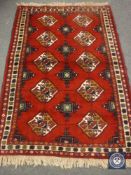 A fringed Persian design rug on red ground,