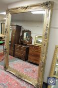 A highly ornate gilt framed floor standing mirror, 7' x 5'.