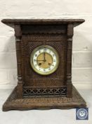 A heavily carved oak cased mantel clock with enamelled dial