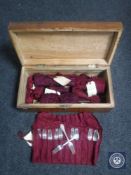 An antique mahogany box of plated cutlery in cloth bags