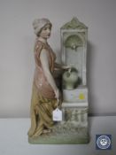 A Royal Dux figure of a lady filling a jug at a fountain,