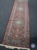 A machine made red floral fringed Turkish runner,