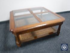 A colonial style square top coffee table with four glass inset panels with undershelf