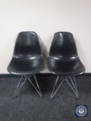 A pair of black plastic Vitra chairs on metal legs