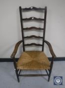 An antique ladder back rush-seated armchair