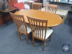 An oval teak G Plan extending dining table and four rail back chairs
