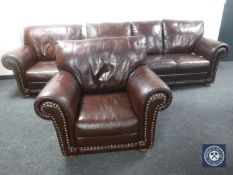 A three-piece brown leather scroll arm suite