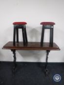 A narrow rectangular pub table on cast iron base together with two upholstered circular stools