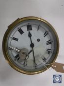 A circular brass cased Smiths ship's clock with enamelled dial and key