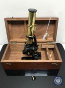 An early 20th century brass and painted metal student microscope in a fitted mahogany box