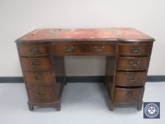 A 20th century mahogany writing desk fitted nine drawers with three tooled-leather inset panels