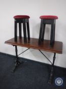 A narrow rectangular pub table on cast iron base together with two upholstered circular stools