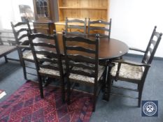 An oval oak extending dining table together with a set of six ladder back chairs
