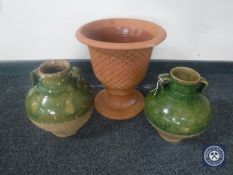 A terracotta planter and two glazed olive jars