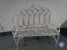 An early 20th century wrought metal two seater arched back garden bench