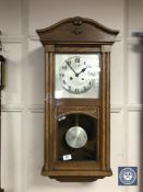 An Edwardian oak wall clock with pendulum and key,