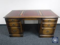 An oak twin pedestal writing desk with three leather inset panels