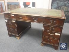 A 20th century mahogany twin pedestal writing desk with a green leather tooled panel