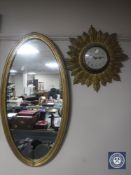 An oval gilt framed mirror together with an early 20th century gilt metal sunburst wall clock with