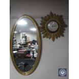 An oval gilt framed mirror together with an early 20th century gilt metal sunburst wall clock with