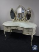 A cream and gilt kidney shaped dressing table with triple mirror and stool