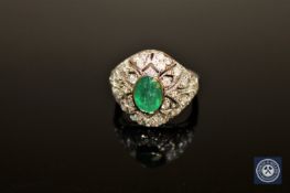 An 18ct white gold emerald and diamond ring, the oval-cut medium-green emerald weighing 0.
