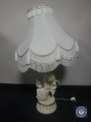A cream and gilt chalk figural cherub table lamp with shade