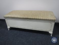 A cream and gilt blanket box upholstered in a striped fabric
