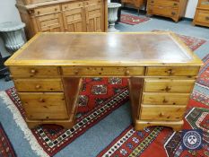 A contemporary pine twin pedestal desk with tooled leather top,
