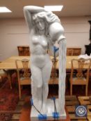 A contemporary carved solid white marble statue of a standing nude female pouring water from a