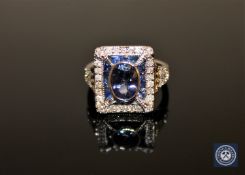 An 18ct white gold tanzanite, sapphire and diamond ring, the central oval-cut tanzanite weighing 0.