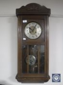 An early 20th century oak wall clock with silvered dial