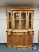 A heavily carved pine serpentine front glazed bookcase,