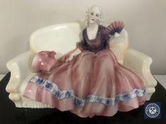 A Kathaus porcelain figure of lady seated on a couch holding a fan