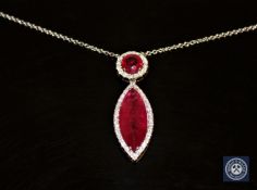 An 18ct white gold ruby and diamond necklace/pendant, a marquise-cut pinkish/red ruby weighing 5.