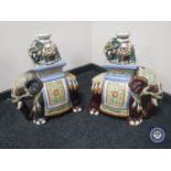 A large pair of pottery elephant stands together with a smaller pair