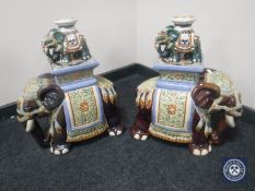 A large pair of pottery elephant stands together with a smaller pair