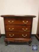 A reproduction mahogany three drawer chest on scroll feet,