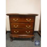 A reproduction mahogany three drawer chest on scroll feet,