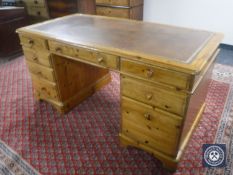 A Ducal Pine twin pedestal writing desk with tooled leather top fitted eight drawers