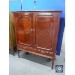 A mahogany double door cabinet on reeded legs