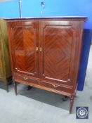 A mahogany double door cabinet on reeded legs