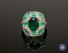 A 14ct white gold emerald and diamond ring, the central, oval-cut, deep-green emerald weighing 1.