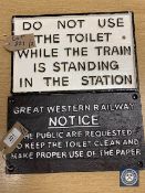 Two metal railway signs : "DO NOT USE THE TOILET WHILE THE TRAIN IS STANDING IN THE STATION" and