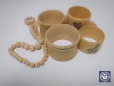 Five antique ivory napkin rings together with a beaded necklace