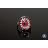 An 18ct white gold ruby and diamond cluster ring, a central oval-cut, deep red ruby weighing 1.