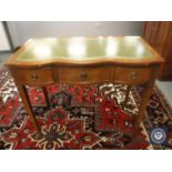 A Georgian style serpentine front desk fitted three drawers, with tooled green leather top,