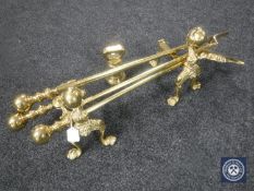 A brass fire companion set with fire dogs and a brass weight